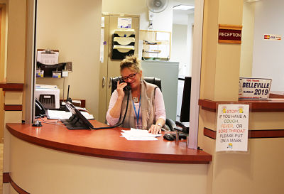 Staff memeber sitting at the reception desk talking on the phone.